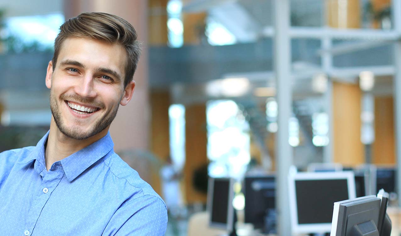 Young man posing confident and positive in professional workplace office with space.