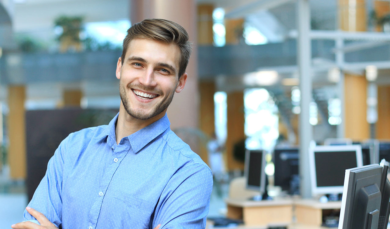 Young man posing confident and positive in professional workplace office with space.