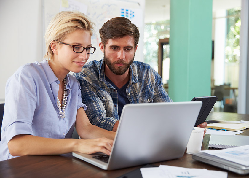 Two Businesspeople Working On Laptop In Office Together